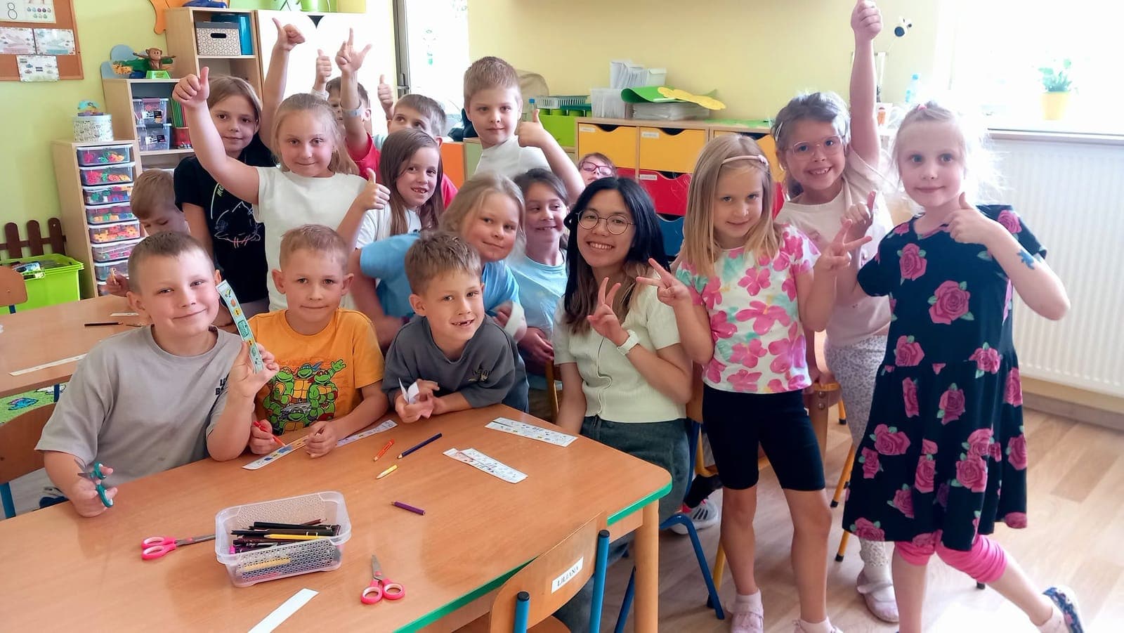 A class of children cheering with their arms up around an exchange participant