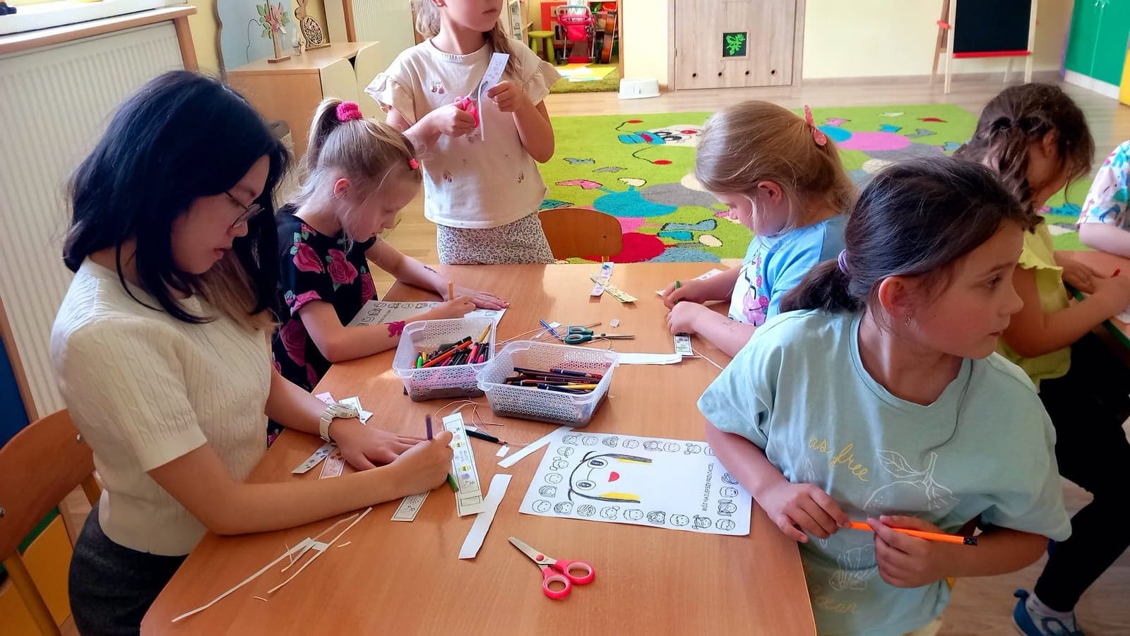 An exchange participant and children making paper crafts at a classroom table