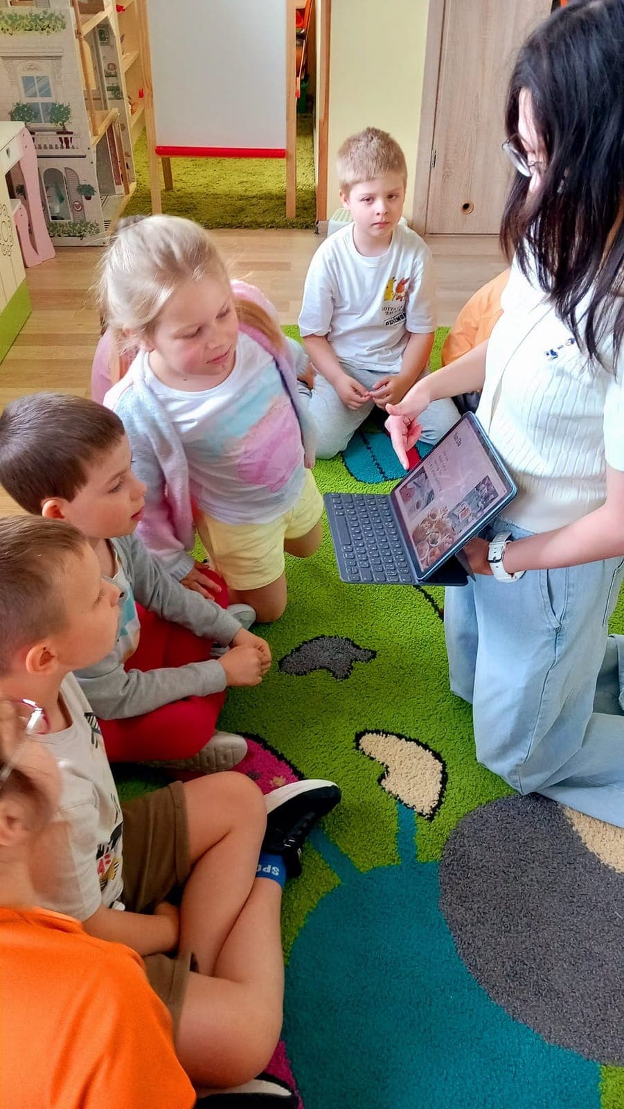 An exchange participant showing something on a tablet to children gathered around her