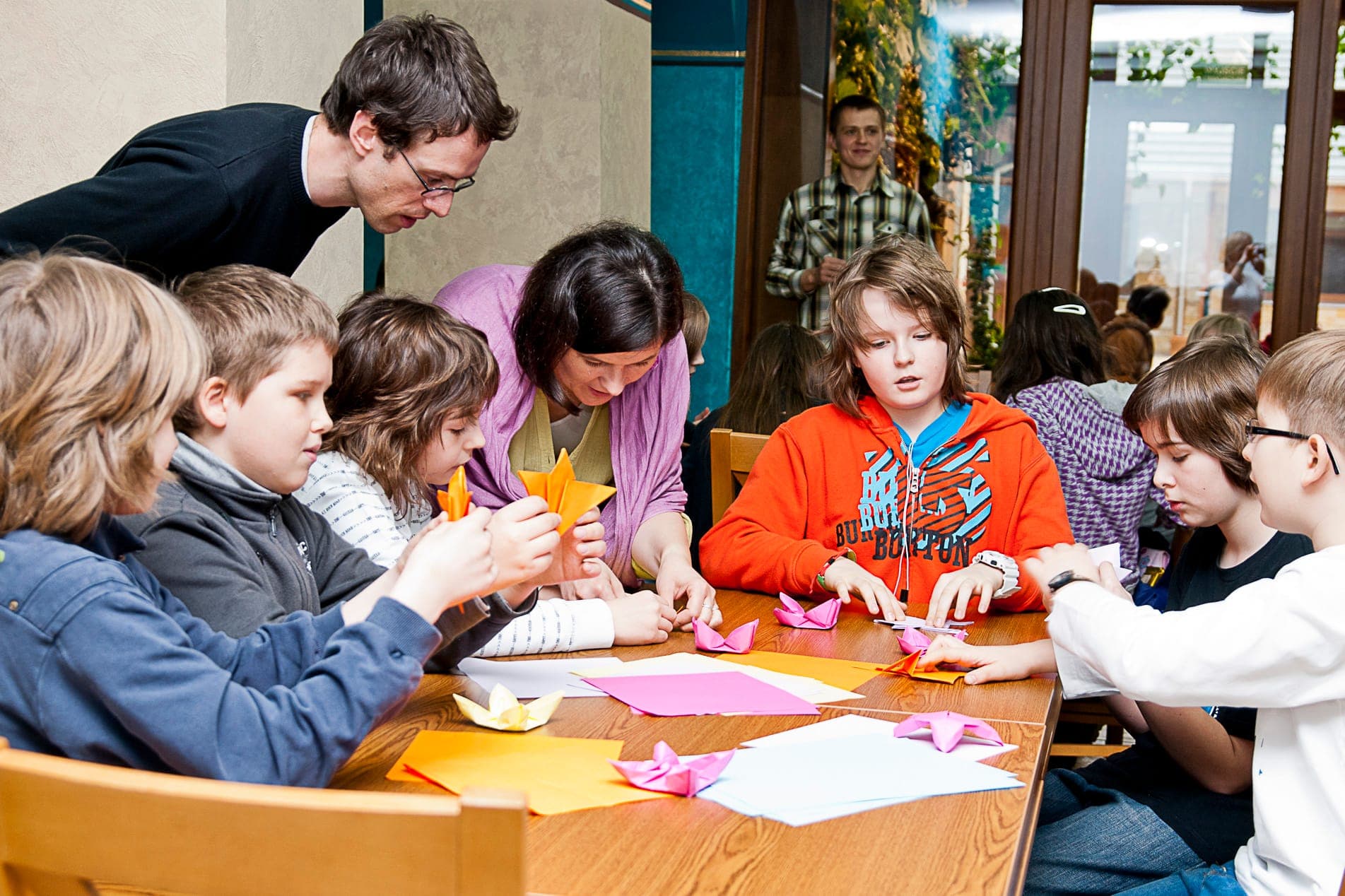 Volunteers helping children fold origami at a community workshop