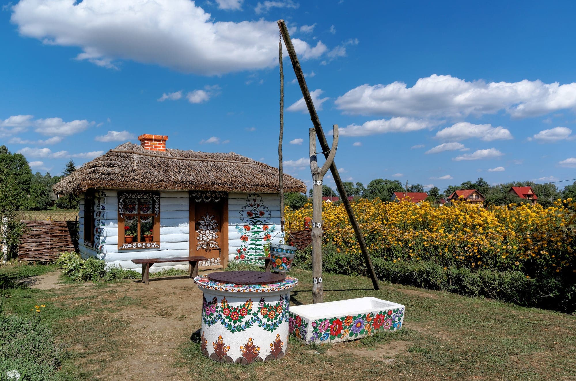 A thatched cottage and well painted with folk flowers in Zalipie